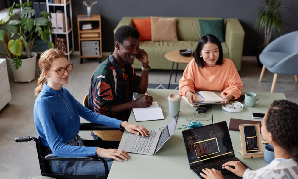 Young diverse IT team meeting at table in office and discussing project